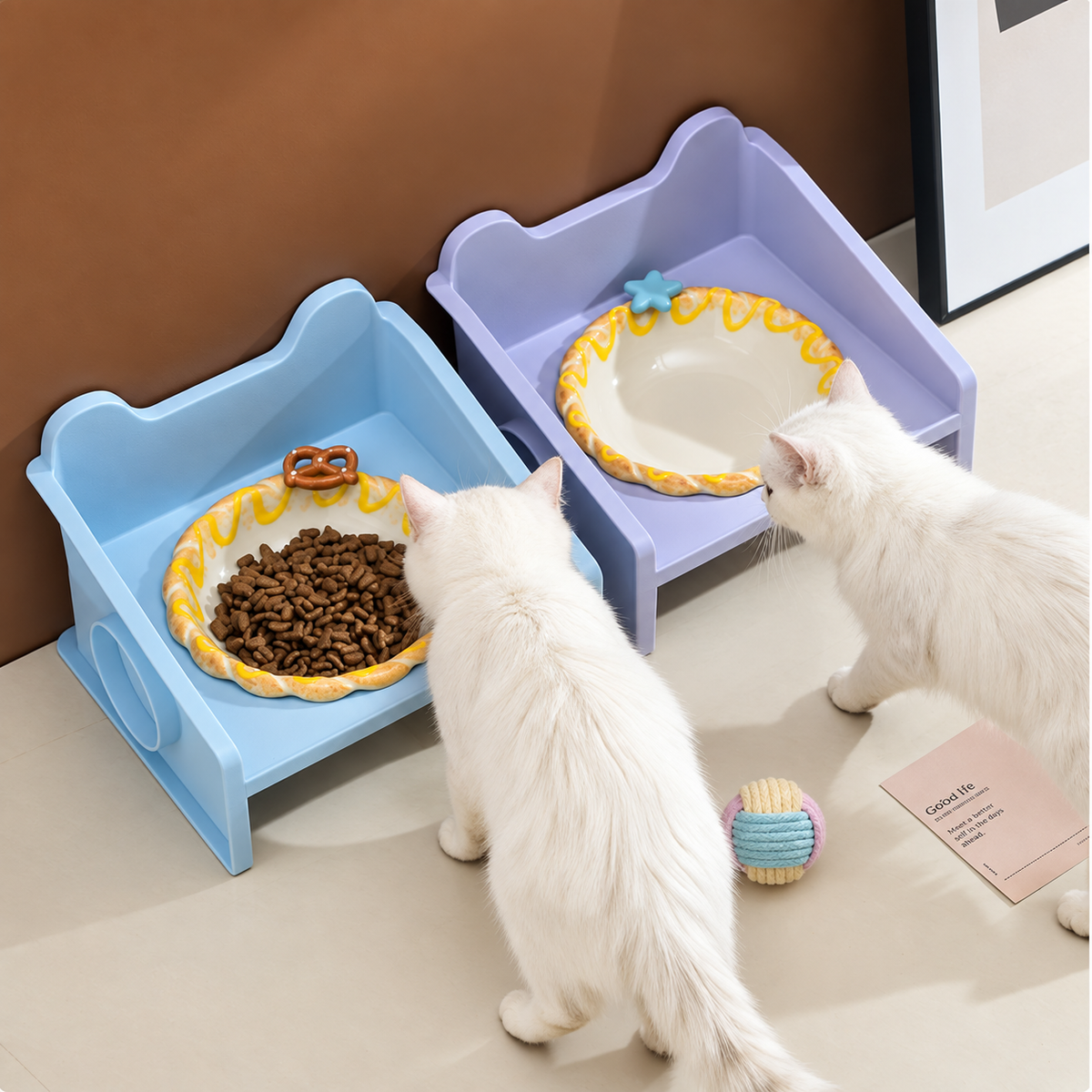 Two white cats using pastel raised ceramic food bowls